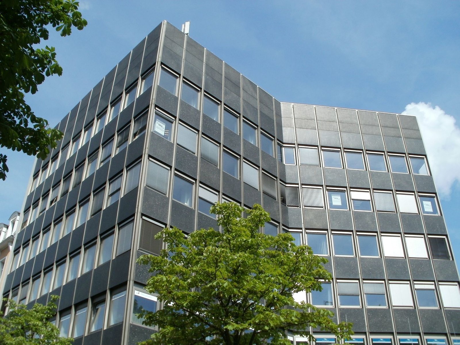 Mehrstöckiges Bürogebäude mit grauer Rasterfassade und großen Fensterfronten – typischer Kandidat für eine gewerbliche Umnutzung