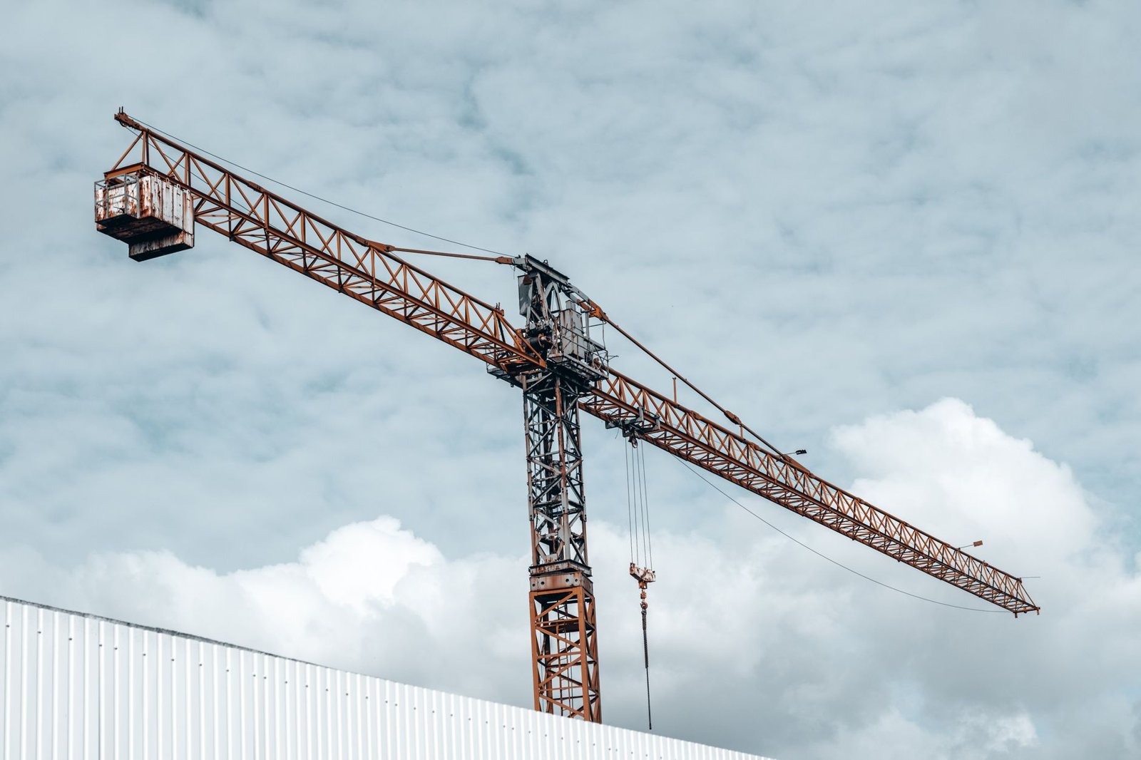 Baukran ragt über die weiße Fassade einer Gewerbe- bzw. Logistikhalle im Rohbau – Gewerbebau für Kühllogistik