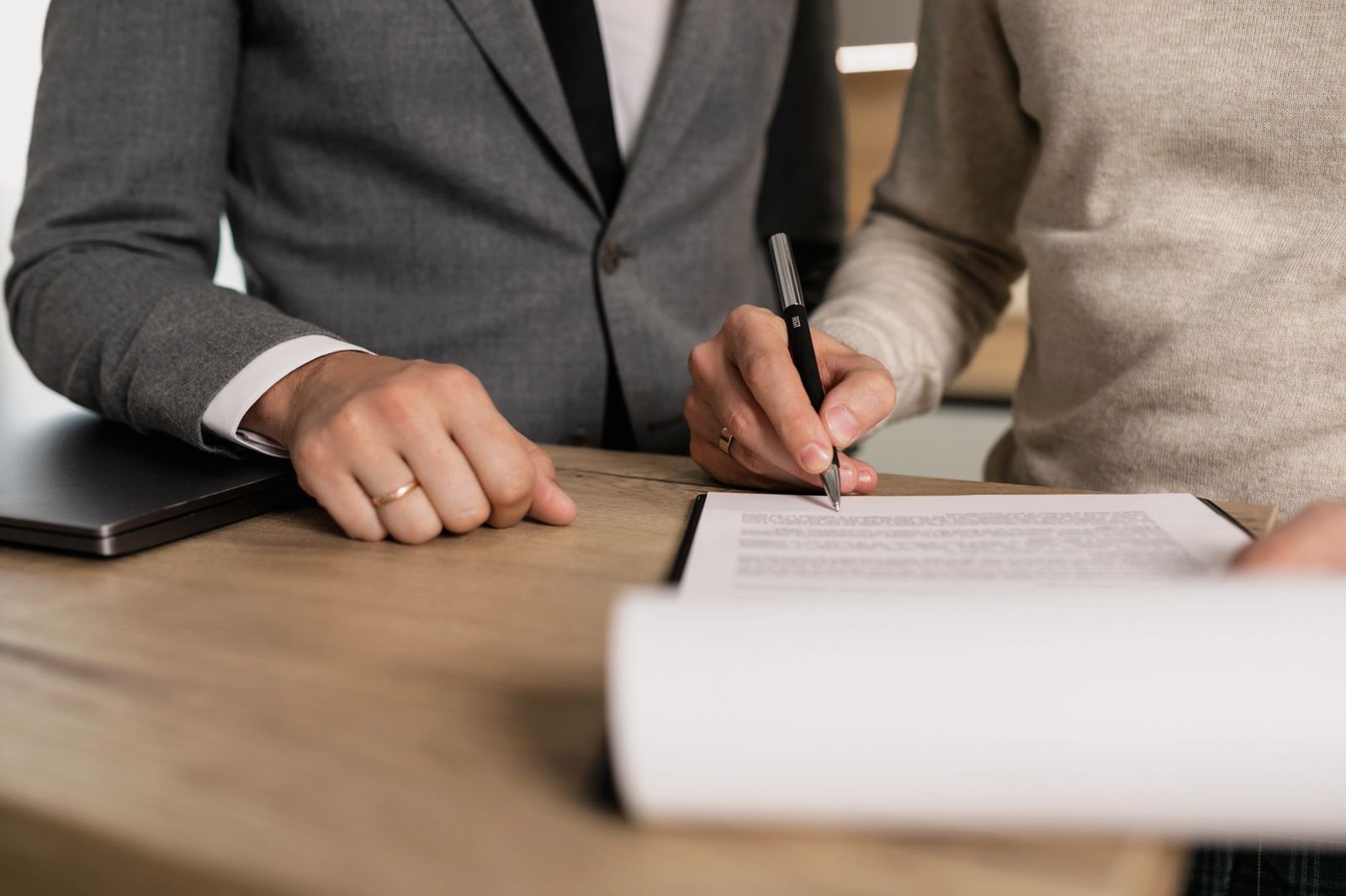 Zwei Personen unterzeichnen gemeinsam ein rechtliches Dokument am Schreibtisch – symbolisiert Vertragspflichten und Sorgfaltspflichten im Lieferkettengesetz