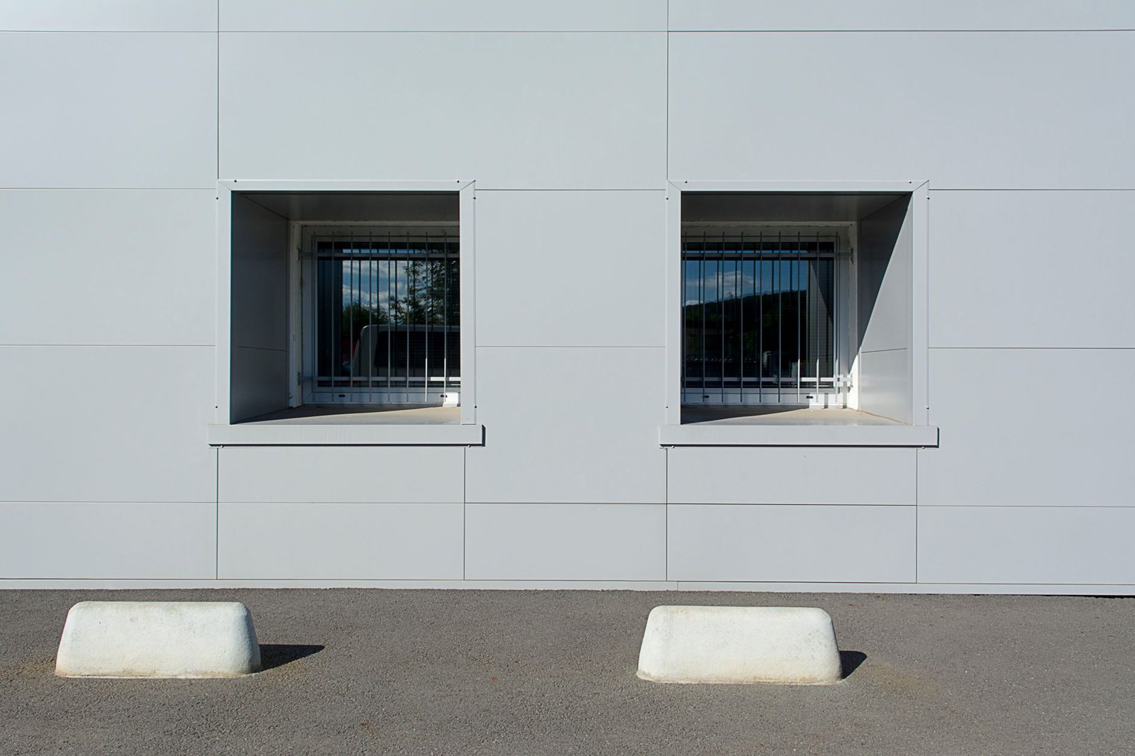 Moderne Gewerbegebäudefassade mit vorgefertigten weißen Fassadenplatten und rechteckigen Fenstern – typisch für serielle Sanierungslösungen an Bestandsimmobilien