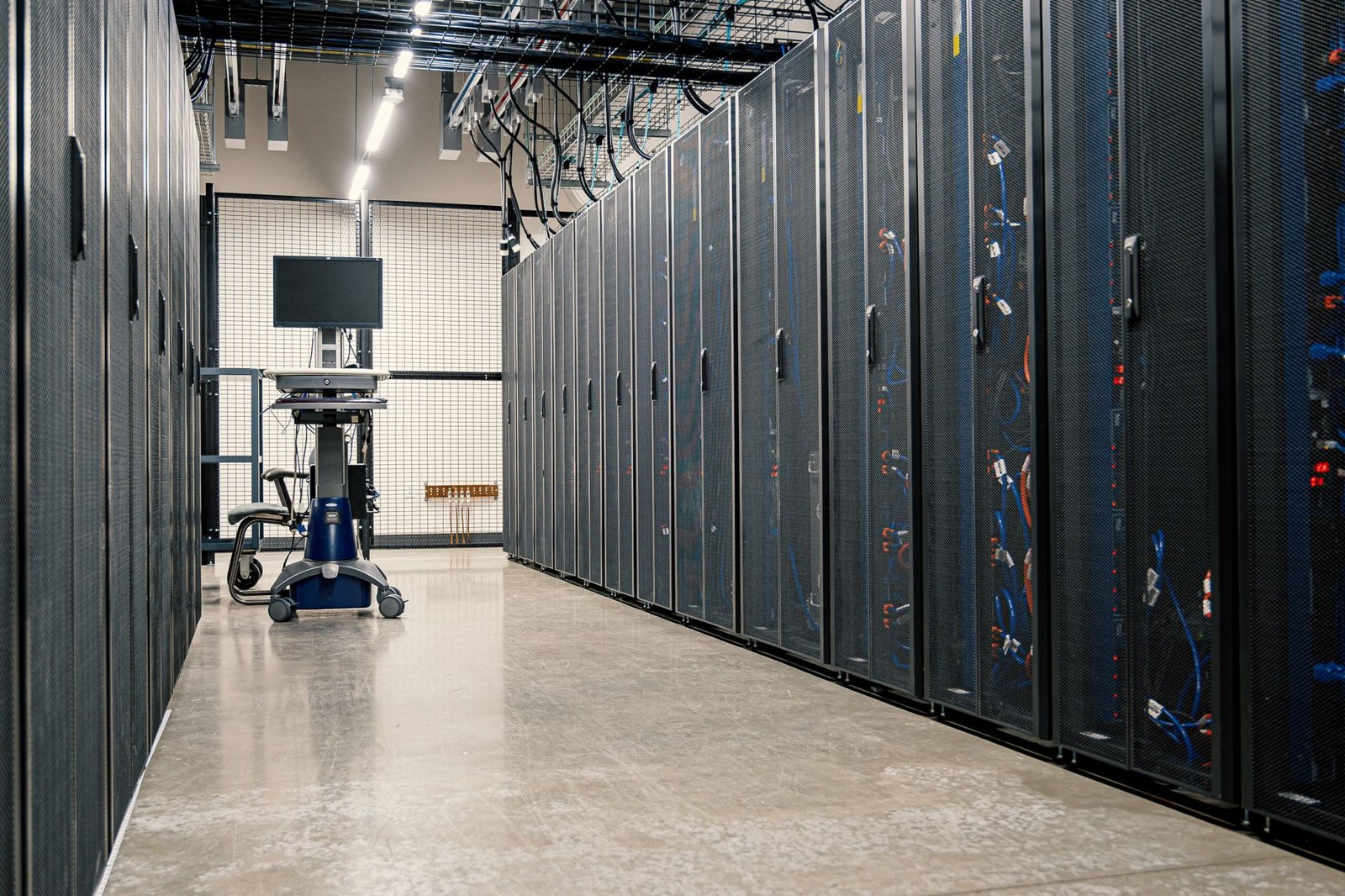 Serverraum mit einer Reihe geschlossener Server-Racks, sichtbarer Kabelführung an der Decke und Betonboden – repräsentativ für die baulichen Anforderungen an Brandschutz, Tragwerk und Kühlung