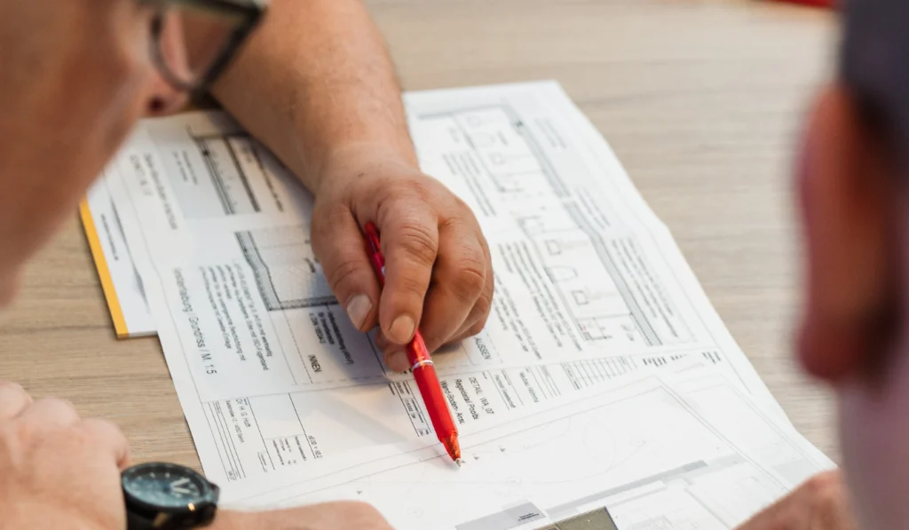 Bauen im Bestand. Drei Personen besprechen einen Bauplan.