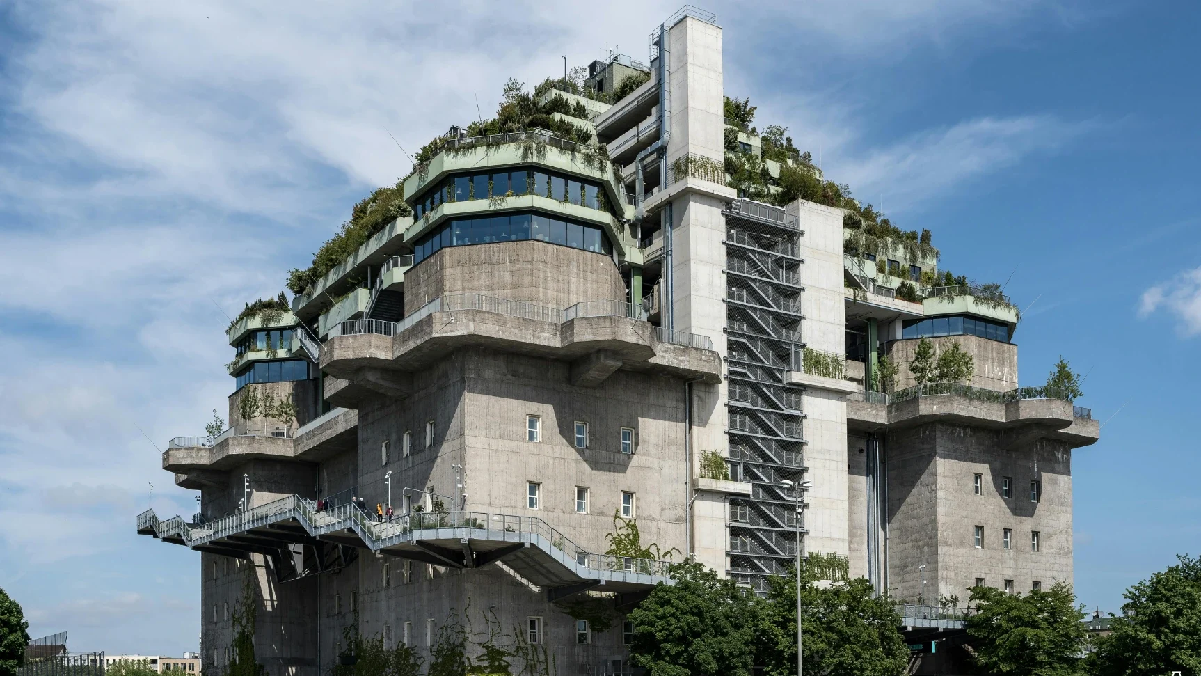 Der begrünte Hamburger Bunker ist vor einem blauen Himmel zu sehen. Er ist ein Beispiel für Öko-Brutalismus.